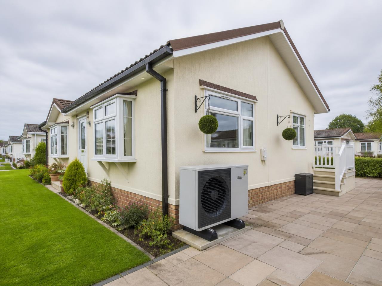 UK park home with a modern air source heat pump installed beside it